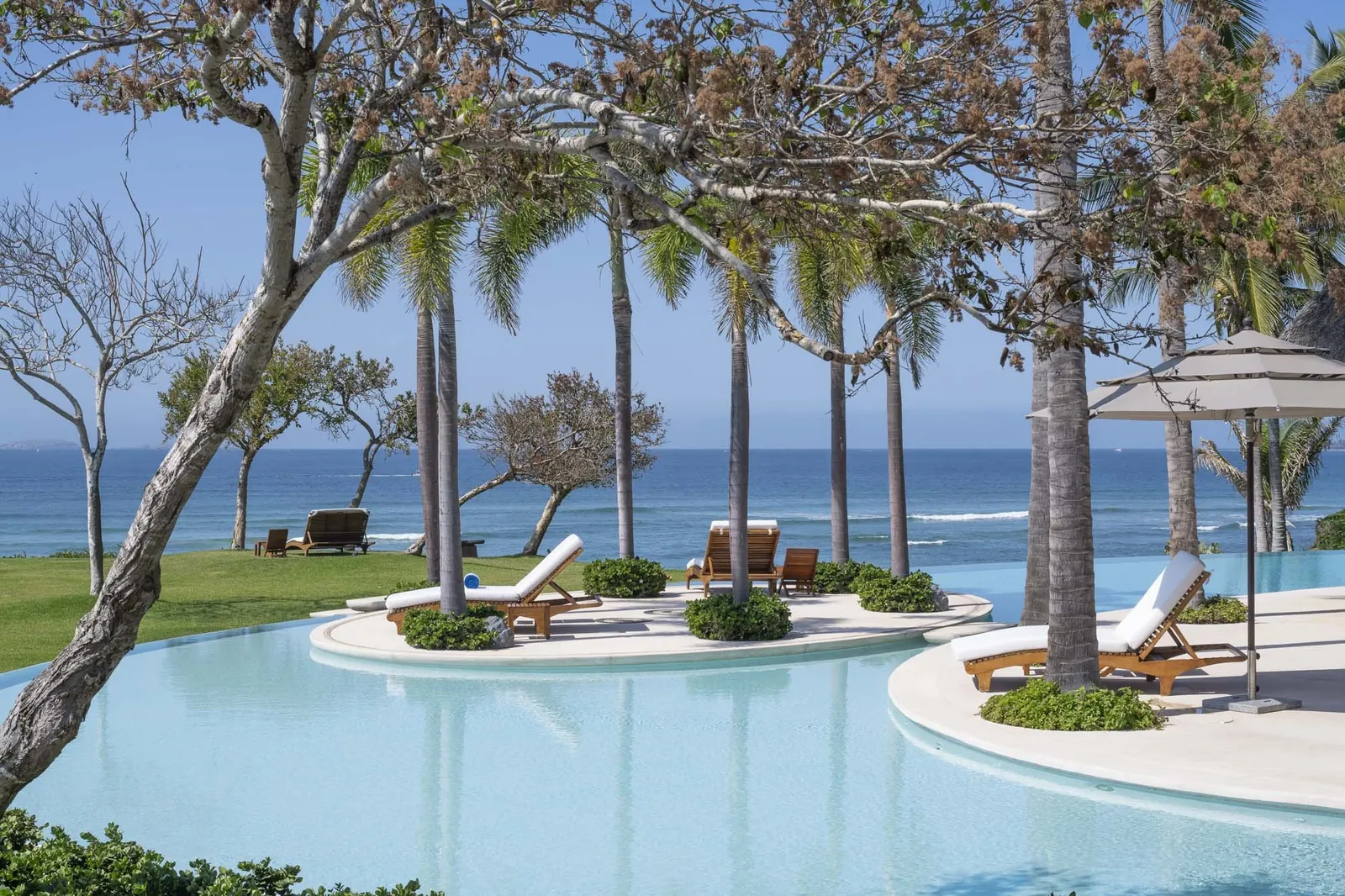 The infinity edge of the pool against the Pacific, sun loungers on the islands