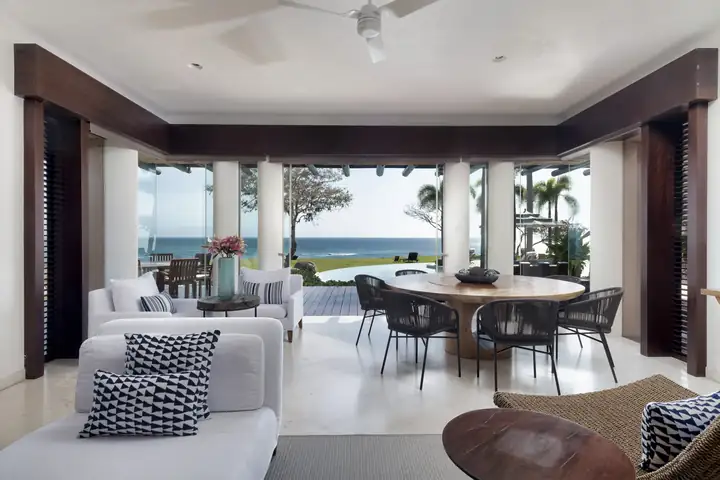 The family room and its round table, glass doors open to the pool