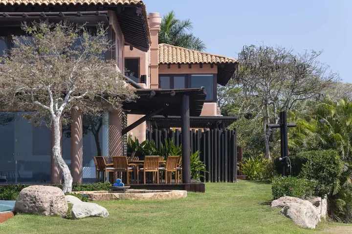 The garden dining terrace beneath the villa, beside the lawn and pool