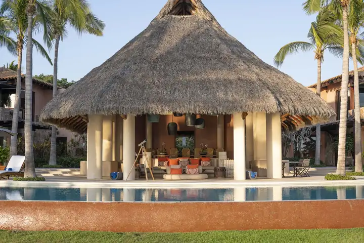 The open-sided palapa seen from the lawn across the pool