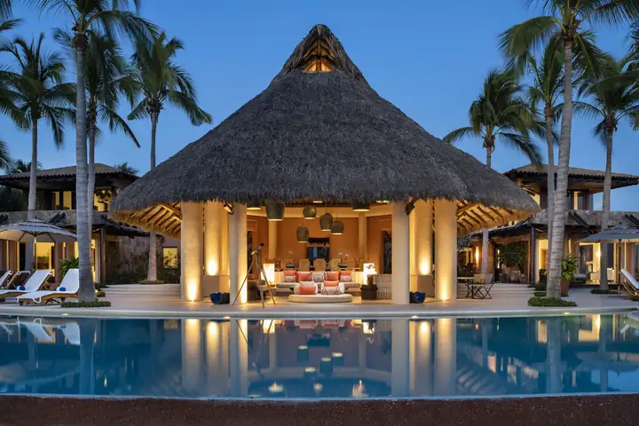 The palapa glowing at blue hour across the pool