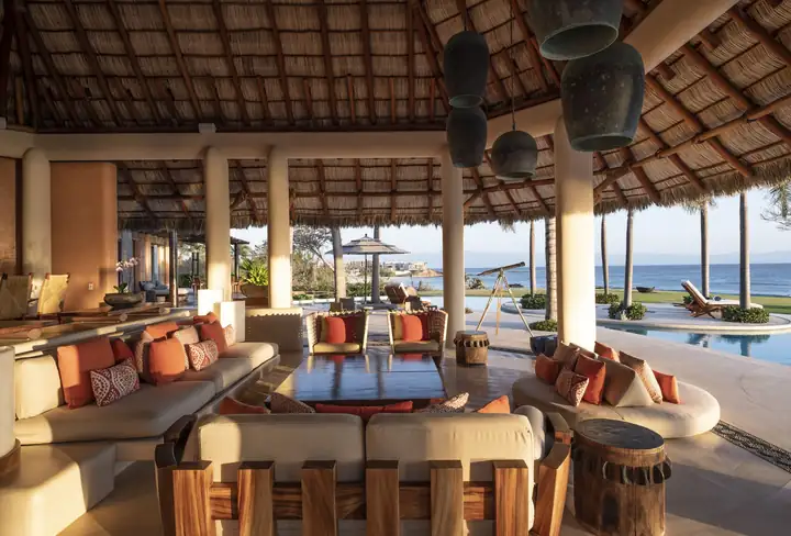 Deep sofas under the palapa, opening straight onto the pool and the sea